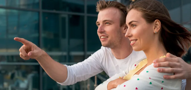 Terapia para relacionamentos, casal jovem sorrindo e apontando para o horizonte, simbolizando conexões fortes e relações saudáveis.