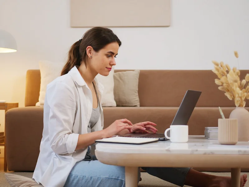 Mulher em sessão de psicoterapia online em casa, sentada com laptop