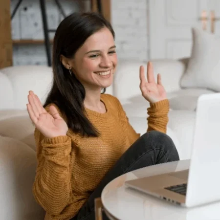 Mulher sorridente em uma sessão de terapia online, acenando para o psicólogo durante uma videochamada.