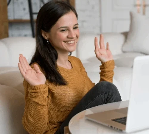 Mulher sorridente em uma sessão de terapia online, acenando para o psicólogo durante uma videochamada.